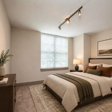 Bedroom with large window bringing in natural light with bed, nightstands, and dresser in dark wood and neutral accents